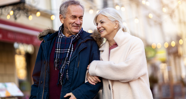 Senior couple smiling walking through the city together in the winter