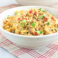 Cauliflower fried rice garnished with chopped scallions in serving bowl.