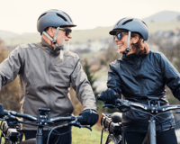  senior couple riding bikes together wearing bike helmets