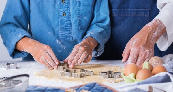 Mature person with alzheimers cutting out holiday cookies with their caregiver.