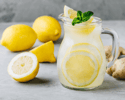 Pitcher of lemonade with lemons and ginger root around it