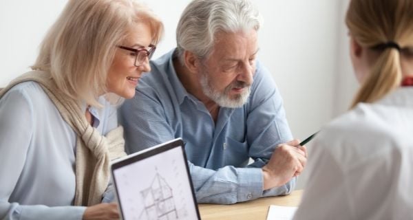 Older couple signing contracts to sell their home.