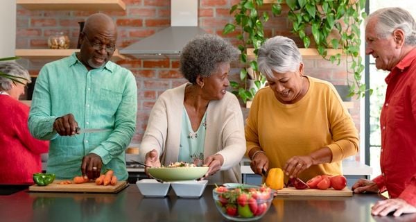 group of mature friends cooking and socializing together