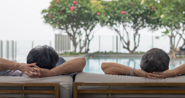 Senior couple relaxing together in front of the pool while on vacation.