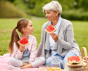Senior woman with her granddaughter on a picnic eating watermelon to keep hydrated
