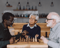 three senior friends playing a game of chess together