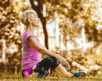  senior woman sitting on a fitness matt outdoors stretching.