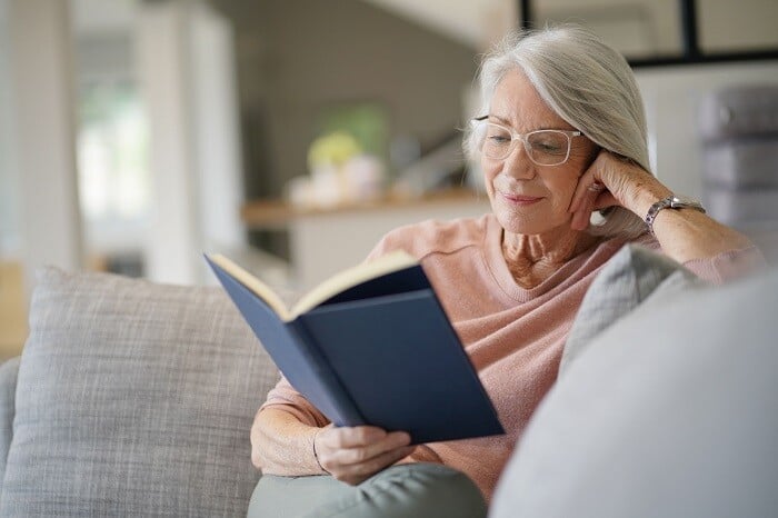  Senior woman reads book at home during COVID-19 quarantine