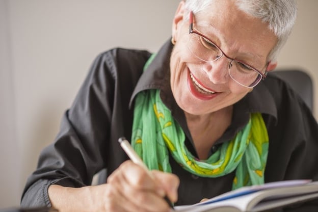Smiling senior woman practices writing in new language