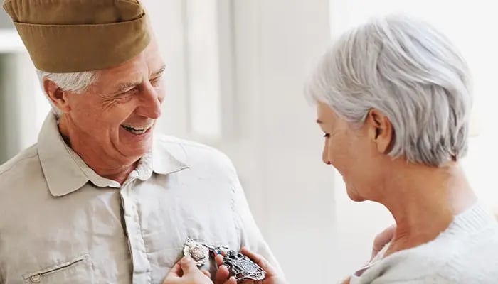 veteran and woman pinning medals on his shirt