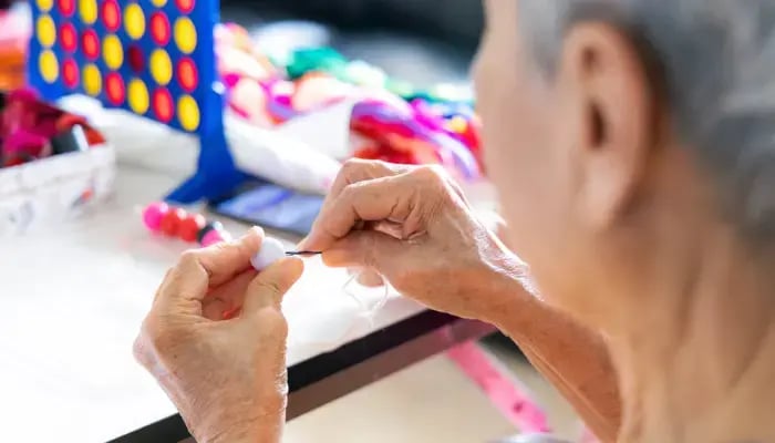 Senior with brain activities such as connect 4, beads, and string