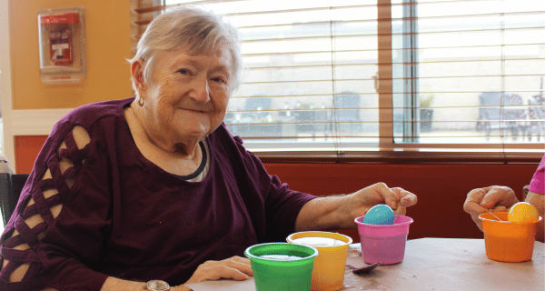 Senior woman smiles while decorating an Easter egg