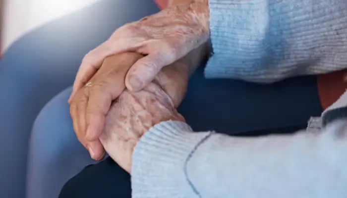 Adult child holding parents hand