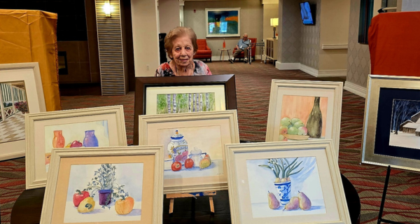 Resident artist at The Bristal at White Plains poses with her creations at the Art Show