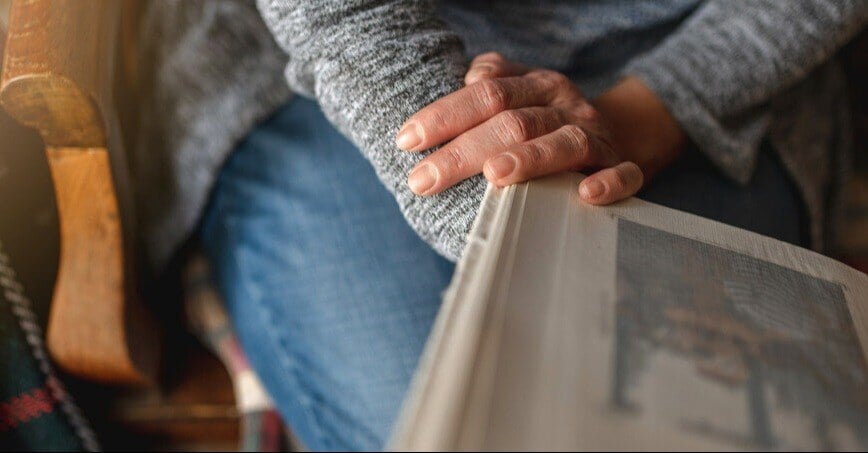 a close up of a person seating, showing hands holding a photo album