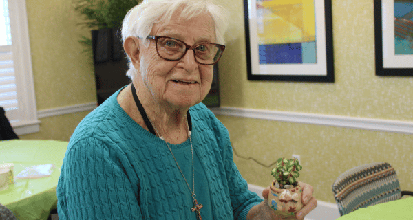 Resident at The Bristal at Somerset displays a succulent she has painted and potted.