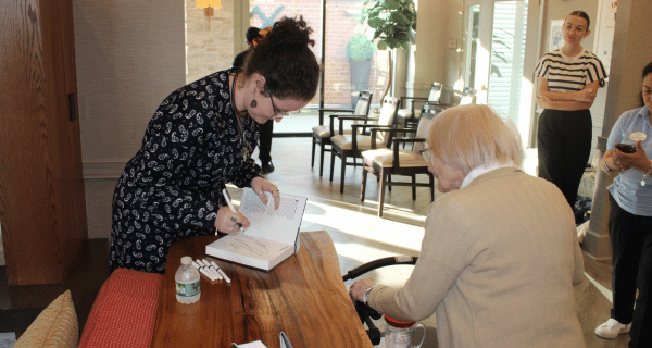 Author Margaret Hall signs a copy of her NYT Bestselling book Gemignani for a senior resident of The Bristal.