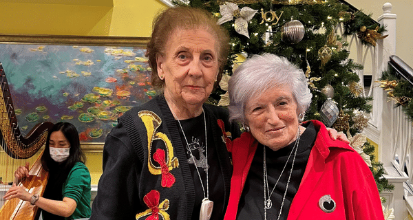 senior women posing for photo in front of holiday tree
