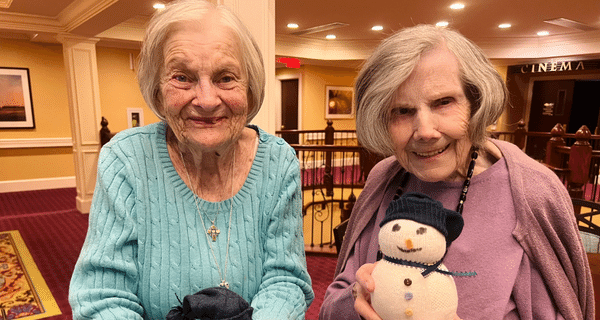senior women holding snowmen and smiling for photo
