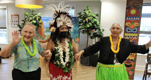 Senior women posing for a picture with a polynesian dancer
