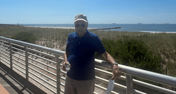 senior man standing on boardwalk in front of the ocean