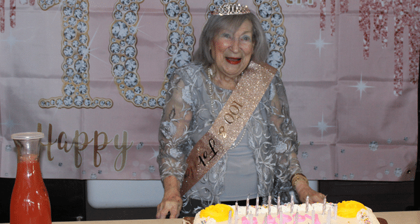senior woman posing for photo with birthday cake