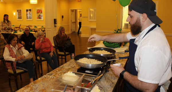 guest chef demonstrates how to make corned beef hash for group of seniors