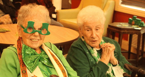 two senior women dressed in green posing for photo