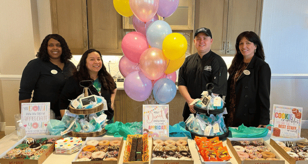 team members standing behind table with baked goods