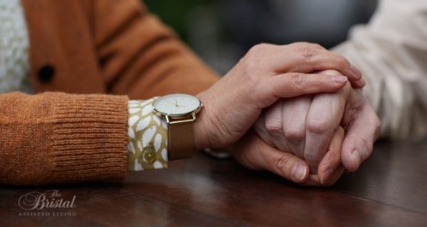 caregiver holding the hand of a senior with vascular dementia