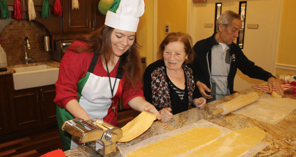 team member and senior couple making fresh pasta