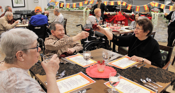 seniors seated at table toasting one another