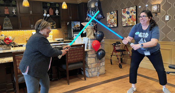 senior woman and team member playing with light sabers