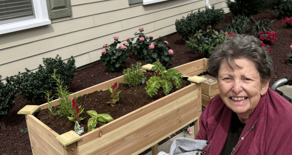 senior woman seated next to raised garden bed