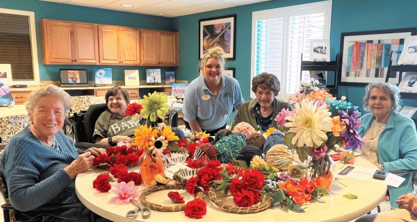 team member and senior women creating floral arrangements