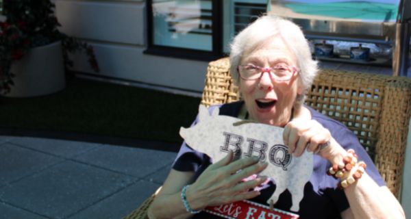 senior woman seated holding a bbq photo prop