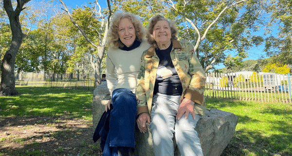 two senior women sitting on a rock
