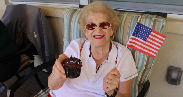 senior woman smiling while holding a chocolate cupcake