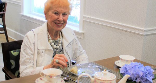 senior woman seated at table with tea service