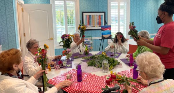 recreation team member helping group of seniors make floral arrangements