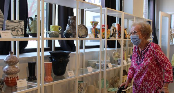 senior woman standing in front of pottery displays