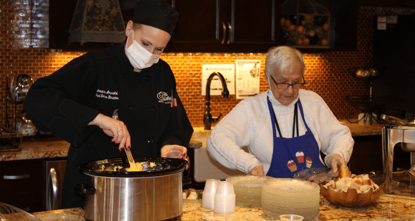 chef and senior woman preparing fondue