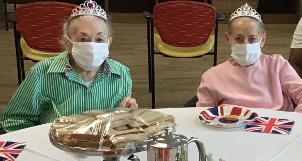 two senior women enjoying a tea service and celebrating Queen Elizabeth's jubilee.