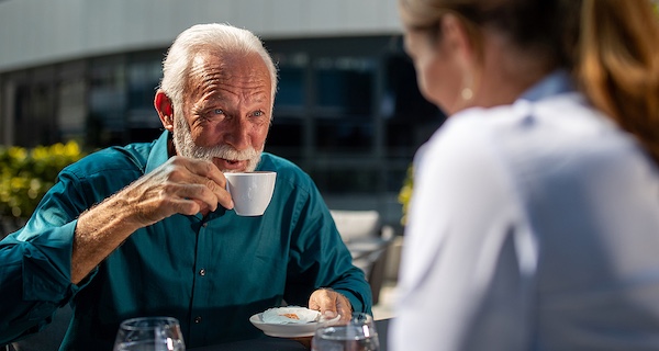 Older business man sips espresso at an outdoor cafe
