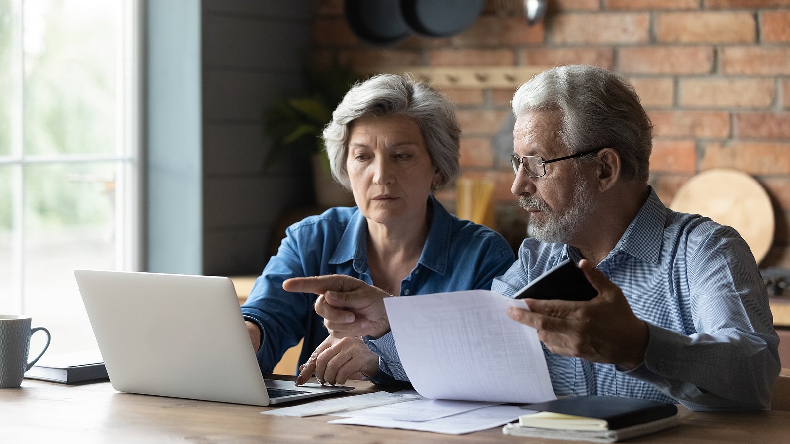Older couple reviewing cost of senior living on a laptop computer in their home