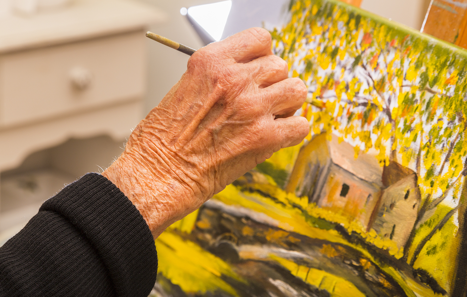 Close-up of a resident participating in a personalized memory care painting activity at The Bristal