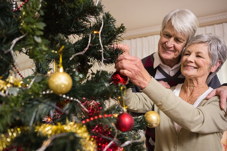 A senior couple embraces while decorating their Christmas tree