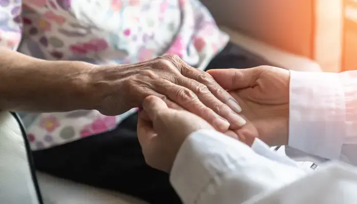 Caregiver holding the hand of a person with Alzheimer’s disease