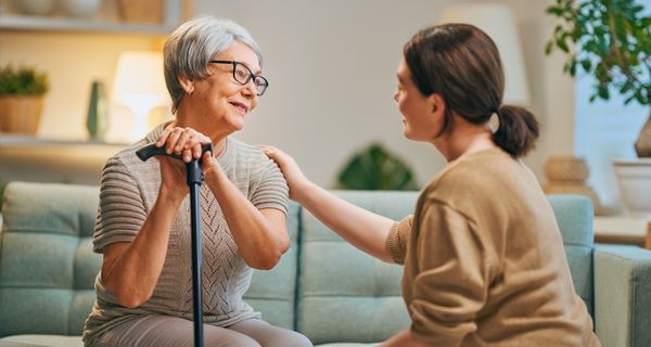 Caregiver sitting and talking with a mature adult.