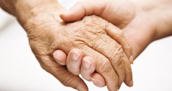 Caregiver holding the hand of someone experiencing delirium.